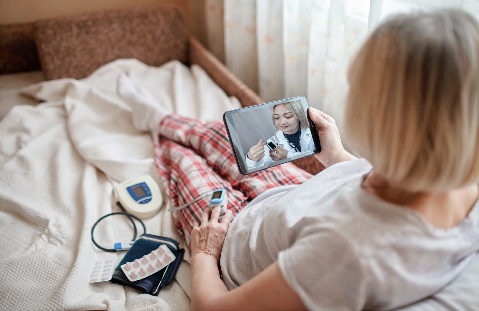 patient looking at an ipad screen talking to her doctor with remote patient monitoring tools hooked up