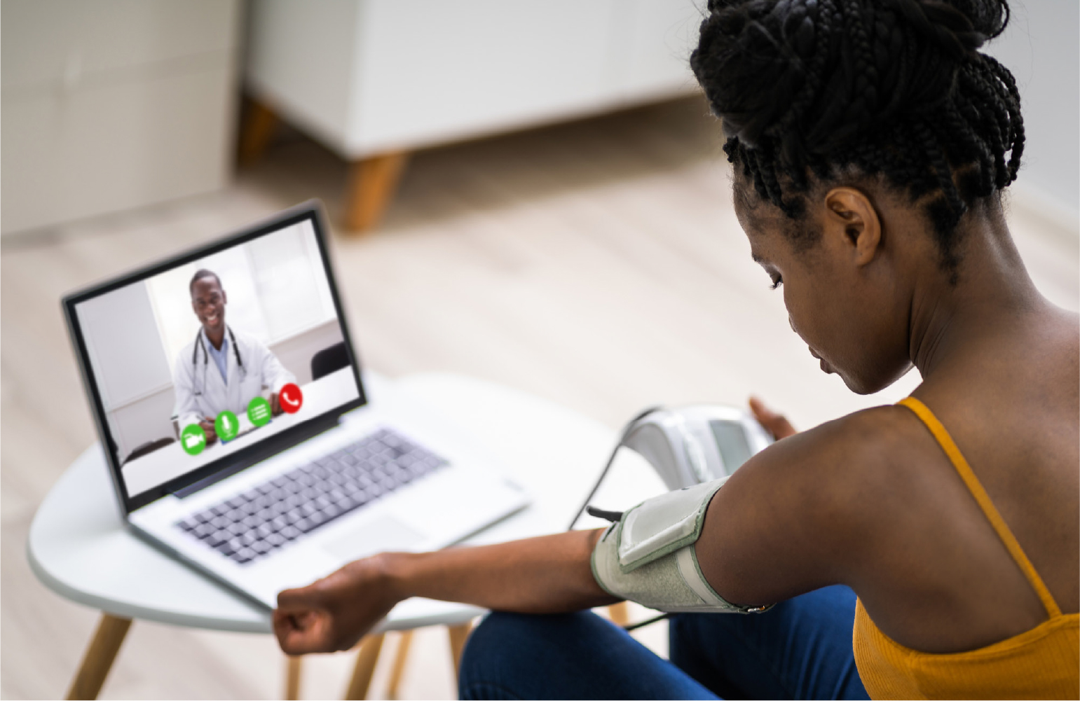 patient taking her blood pressure with laptop in front of her talking to her doctor