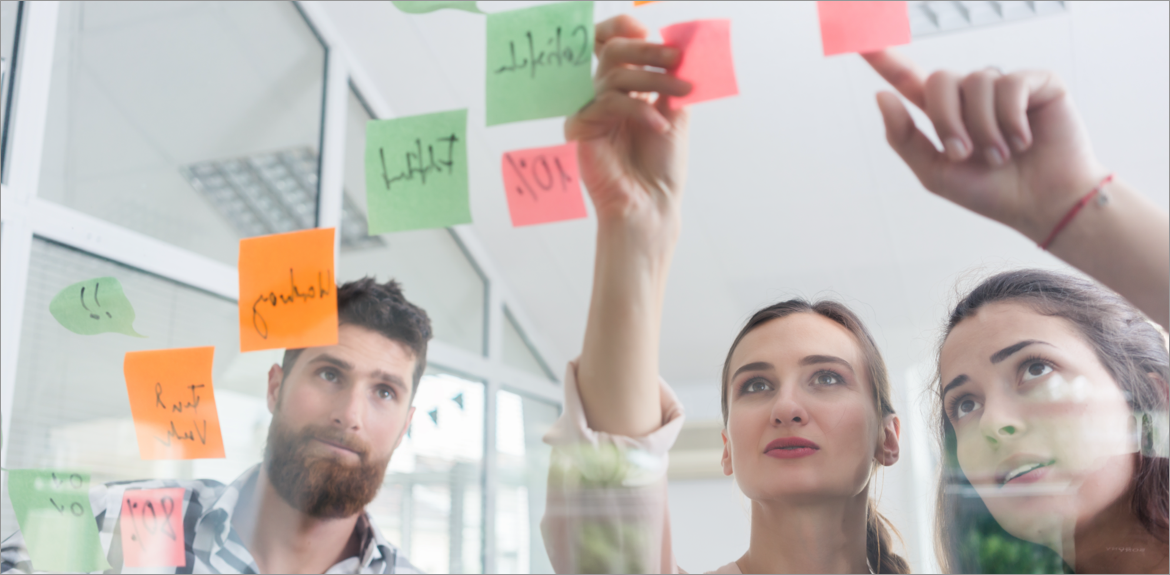 On The Blog: We're listening: How your feedback helps us build a better EHR experience. Photograph of three workers posting ideas to a board in an office.